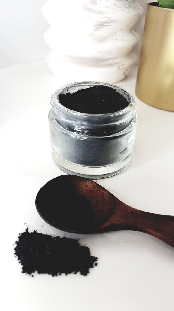activated charcoal scrub in glass jar with wooden spoon